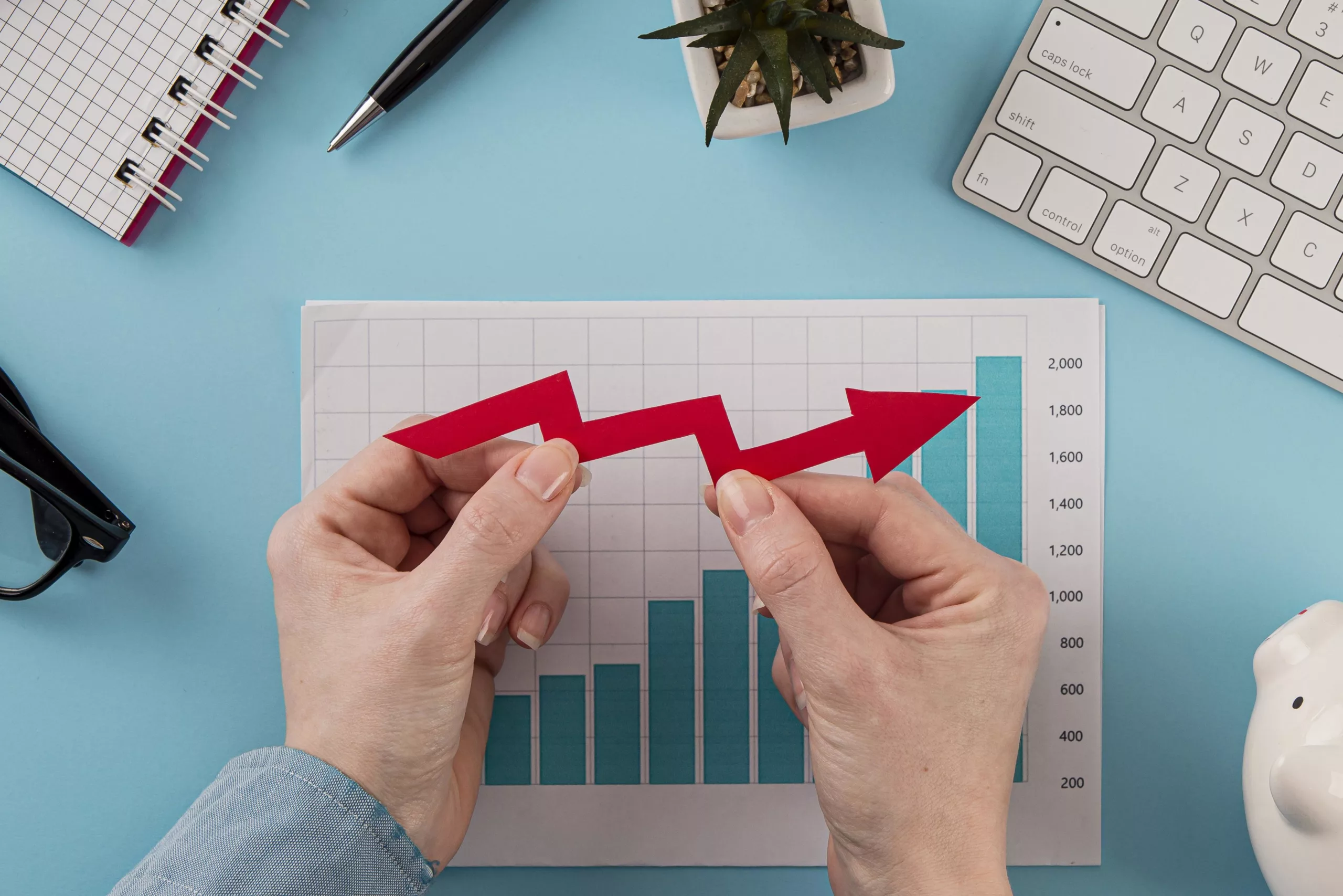 top view of business items with growth chart and hands holding arrow scaled